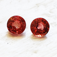 Pretty pair of lively 5 mm round reddish orange sapphires. This 5 millimeter round pair of orange red sapphires are very bright and perfect for earrings or side stones.